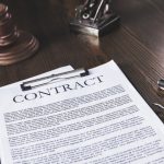juridical contract on wooden table with pen and hammer, law concept